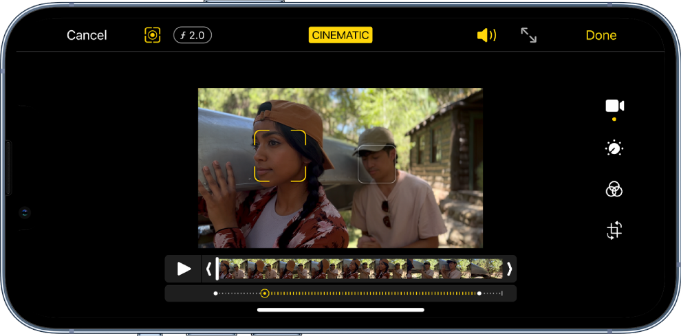 Cinematic režīma video rediģēšanas ekrāns ainavas orientācijā. Ekrāna augšējā kreisajā stūrī ir poga Cancel, poga Cinematic Manual un poga Depth Adjustment. Pa visu ekrāna augšpusē ir atlasīta poga Cinematic. Ekrāna augšējā labajā stūrī ir poga Volume, poga Enter Full Screen un poga Done. Video atrodas ekrāna centrā, un ap fokusa subjektu ir ietvars. Zem video atrodas kadru skatītājs, kas attēlo punktu videoklipā, kur mainās subjekta fokuss. Rediģēšanas rīki atrodas ekrāna labajā pusē no augšas līdz lejai: Video, Adjust Color, Filter un Crop.